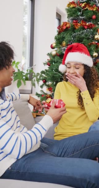 Vídeo Vertical Feliz Pareja Diversa Intercambiando Regalo Navidad Abrazando Casa — Vídeos de Stock