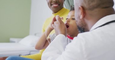 Afro-Amerikan erkek doktor çocuk hastayı hastanede muayene ediyor. Tıp, sağlık, yaşam tarzı ve hastane konsepti.