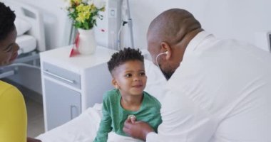 Hastanede steteskop kullanarak çocuk hastaları muayene eden Afrikalı Amerikalı erkek doktor. Tıp, sağlık, yaşam tarzı ve hastane konsepti.