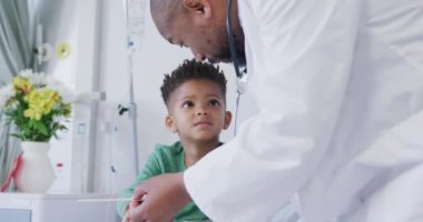 Afro-Amerikan erkek doktor çocuk hastayı hastanede muayene ediyor. Tıp, sağlık, yaşam tarzı ve hastane konsepti.