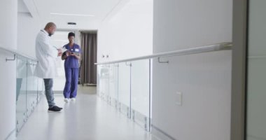 Afro-Amerikan erkek ve kadın doktorlar ellerinde dosya ve tablet, hastanede konuşuyorlar. Tıp, sağlık, yaşam tarzı ve hastane konsepti.