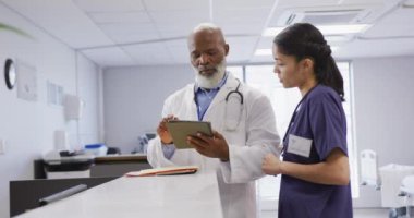 Tablet kullanan ve hastanede konuşan çeşitli erkek ve kadın doktorlar. Tıp, sağlık, yaşam tarzı ve hastane konsepti.
