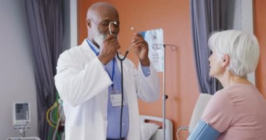 Afrika kökenli Amerikalı erkek doktor, hastanedeki beyaz kadın hastayı muayene ediyor. Tıp, sağlık, yaşam tarzı ve hastane konsepti.