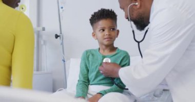 Hastanede steteskop kullanarak çocuk hastaları muayene eden Afrikalı Amerikalı erkek doktor. Tıp, sağlık, yaşam tarzı ve hastane konsepti.