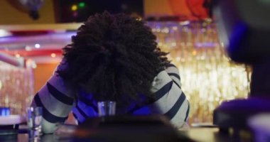 Çok içtikten sonra kafası öne eğik oturan sarhoş Afro-Amerikan bir adamın videosu. İçmek, dışarı çıkmak ve alkol konsepti.