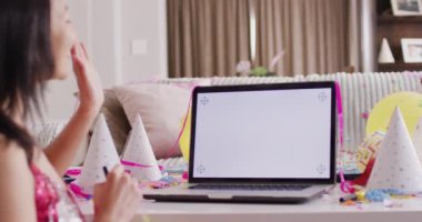 Dizüstü bilgisayarında pembe elbise giymiş, boş ekran görüntülü gülümseyen melez kadının videosu. Parti, boş zaman, ev hayatı ve yaşam tarzı konsepti.