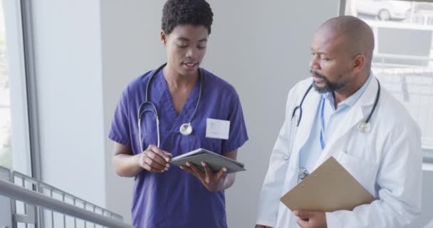 非洲裔美国男女医生手持剪贴板和平板电脑 在医院里交谈 生活方式和医院概念 — 图库视频影像