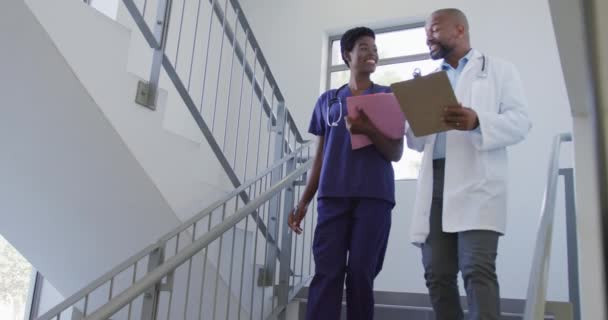 非裔美国男女医生手握剪贴板 在医院里交谈 生活方式和医院概念 — 图库视频影像