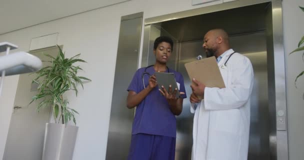 非洲裔美国男女医生手持剪贴板和平板电脑 在医院里交谈 生活方式和医院概念 — 图库视频影像
