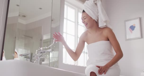 Banyodaki Küvette Oturan Saçında Havlu Olan Gülümseyen Melez Kadının Videosu — Stok video