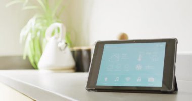 Akıllı ev arayüzü ekranlı tablet videosu atölyede, güneşli ve modern mutfakta. Teknoloji, kontrol, ekoloji ve ev hayatı.