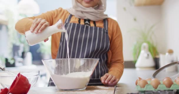 Video Glad Biracial Kvinde Hijab Bagning Køkkenet Derhjemme Hælde Mælk – Stock-video