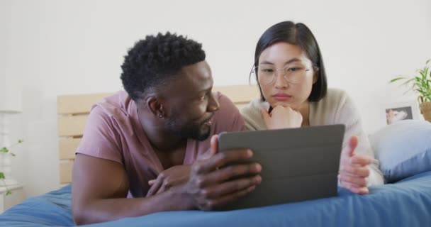 Happy Diverse Couple Using Tablet Lying Bedroom Spending Quality Time — Vídeo de stock