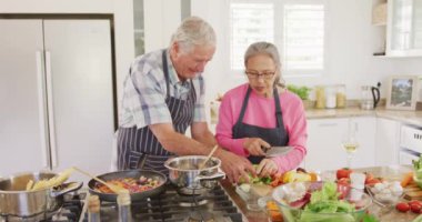 Önlük giyip mutfakta yemek pişiren mutlu son sınıf çifti. Etkin emeklilik ve yaşam tarzı kavramı.
