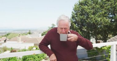 Kafkasyalı üst düzey bir adam balkonda bir fincan kahveyle rahatlıyor. Etkin emeklilik ve yaşam tarzı kavramı.