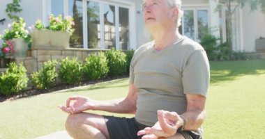 Mutlu Kafkasyalı son sınıf öğrencisi bahçede yoga ve meditasyon yapıyor. Etkin emeklilik ve yaşam tarzı kavramı.