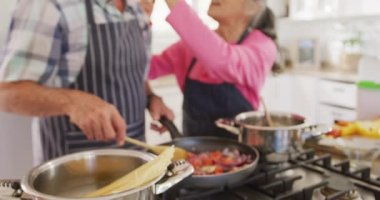 Önlük giyip mutfakta yemek pişiren mutlu son sınıf çifti. Etkin emeklilik ve yaşam tarzı kavramı.