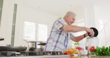 Kafkasyalı kıdemli adam mutfaktan atıkları atıyor ve yemek yapıyor. Etkin emeklilik ve yaşam tarzı kavramı.