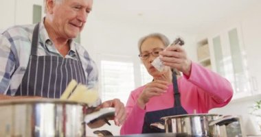 Önlük giyip mutfakta yemek pişiren mutlu son sınıf çifti. Etkin emeklilik ve yaşam tarzı kavramı.