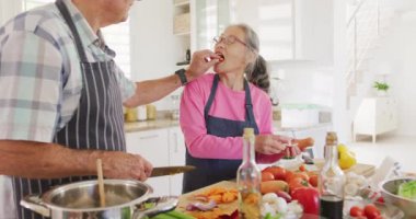 Önlük giyip mutfakta yemek pişiren mutlu son sınıf çifti. Etkin emeklilik ve yaşam tarzı kavramı.