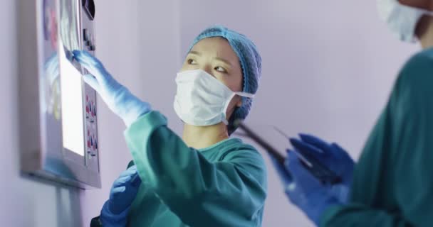 亚洲女外科医生在手术室与同事讨论X光的录像 医疗和保健服务 — 图库视频影像