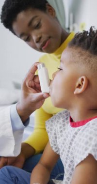 Afro-Amerikan erkek doktorun hastanedeki çocuk hastayı muayene edişinin dikey videosu. Tıp, sağlık, yaşam tarzı ve hastane konsepti.