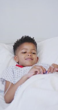 Afro-Amerikan çocuğun hastanede yatarken çekilmiş dikey videosu. Tıp, sağlık, yaşam tarzı ve hastane konsepti.