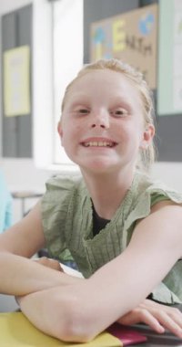 Sınıfta, fotokopi odasında oturan mutlu beyaz kız öğrencisinin dikey video portresi. Eğitim, çocukluk, okul ve öğrenme kavramı.