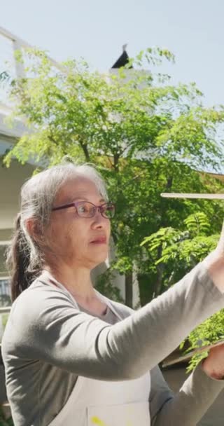 Verticale Video Van Aziatische Senior Vrouw Schilderen Tuin Zonnige Dag — Stockvideo