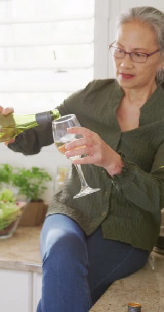 Κάθετο Βίντεο Χαρούμενη Ασιάτισσα Ηλικιωμένη Πίνει Κρασί Στην Κουζίνα Έννοια — Αρχείο Βίντεο