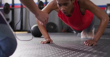Video of diverse fitness trainer and woman doing push ups high fiving at a gym. Exercise, fitness and healthy lifestyle.