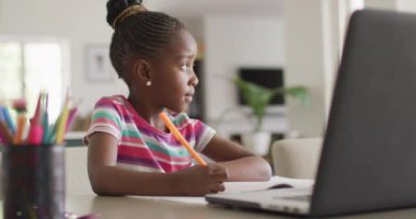 Düşünceli Afrikalı Amerikalı bir kızın online derste evdeki dizüstü bilgisayarında yazdıklarının videosu. Eğitim, öğrenim, teknoloji ve ev hayatı.