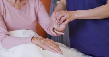 İki ırklı kadın doktor, hastanedeki Kafkas kadın hastasının elini inceliyor. Tıp, sağlık, yaşam tarzı ve hastane konsepti.