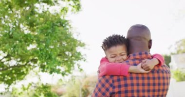 Happy african american father and his son embracing in garden. Spending quality time at home.