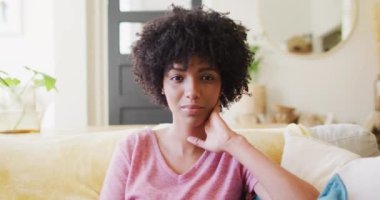 Video portrait of smiling biracial woman relaxing at home, with copy space. Happiness, relaxation and domestic life.