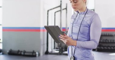 Video of concentrating caucasian female fitness trainer using tablet at a gym. Exercise, fitness and healthy lifestyle.