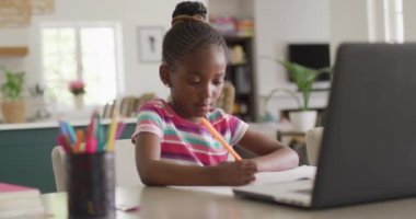 Düşünceli Afrikalı Amerikalı bir kızın online derste evdeki dizüstü bilgisayarında yazdıklarının videosu. Eğitim, öğrenim, teknoloji ve ev hayatı.