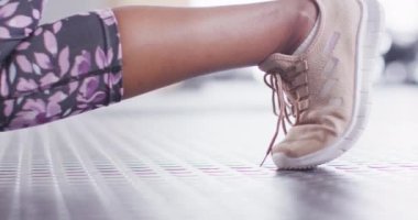 Video of low section of african american woman doing lunges with kettlebells at gym. Exercise, fitness and healthy lifestyle.