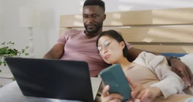 Laptop kullanan ve yatak odasında yatan mutlu çift. Ev kavramında kaliteli zaman geçirmek.
