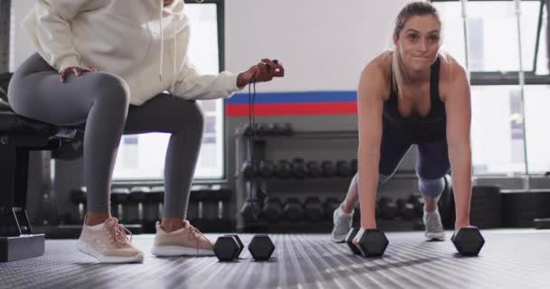 Video Diverse Female Fitness Trainer Timing Determined Woman Raising Dumbbells — Vídeo de stock