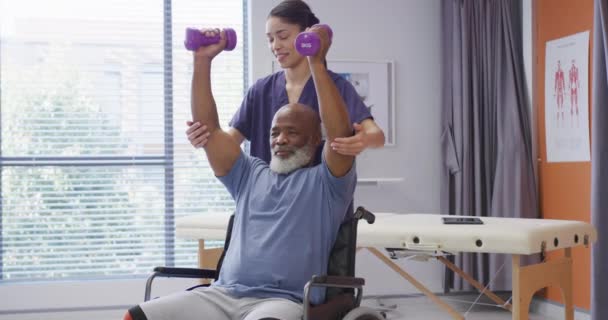 Çeşitli Kadın Fizyoterapist Yaşlı Erkek Hasta Fizik Tedavi Seansında Dambıl — Stok video