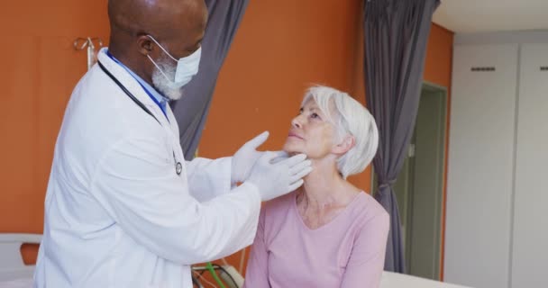 在医院检查老年白人女病人颈部的非裔美国男性医生 生活方式和医院概念 — 图库视频影像