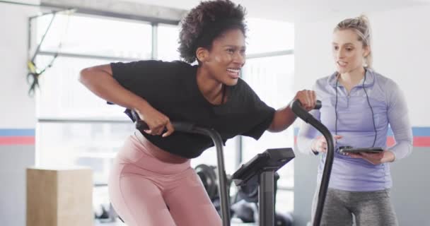 不同的女性健身教练和在健身房锻炼自行车的女性的视频 健身和健康的生活方式 — 图库视频影像