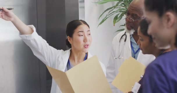 Vídeo Tres Médicos Diversos Hombres Mujeres Mirando Archivo Hablando Corredor — Vídeos de Stock