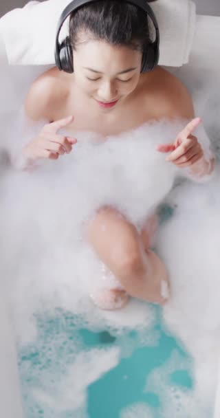 Vertical Video Smiling Biracial Woman Headphones Bathtub Bathroom Health Beauty — Video Stock