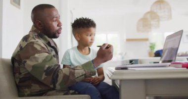 African american father with son learning together with laptop. Spending quality time together, army and patriotism concept.