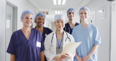 Video of diverse group of happy medical workers in surgical caps smiling in hospital corridor. Hospital, medical and healthcare services.