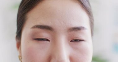Video close up portrait of the opening and smiling eyes of asian female 