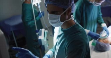 Video of midsection of surgical assistant giving gas to asian female patient in operating theatre. Hospital, medical and healthcare services.
