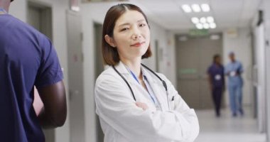 Hastanenin yoğun koridorunda duran gülümseyen Asyalı kadın doktorun video portresi, kopyalama alanı. Hastane, sağlık ve sağlık hizmetleri.